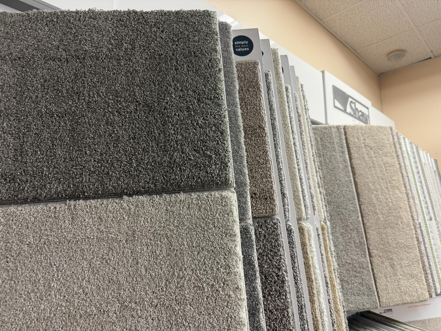 Plush and textured carpet samples stacked on a rack in the Express Carpet showroom