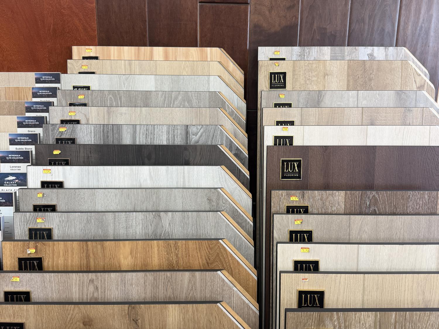 LUX Flooring laminate plank samples fanned out against a dark hardwood display wall in Anaheim