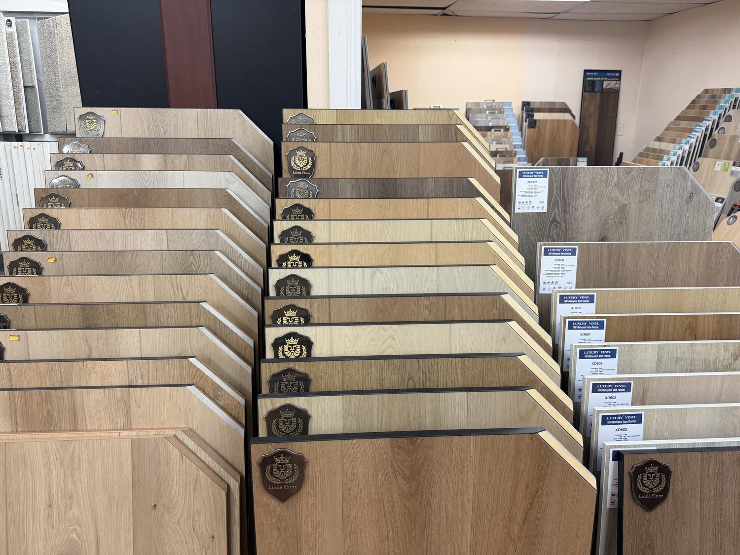 Lions Floor luxury vinyl plank samples on a showroom rack beside waterproof rigid-core spec cards