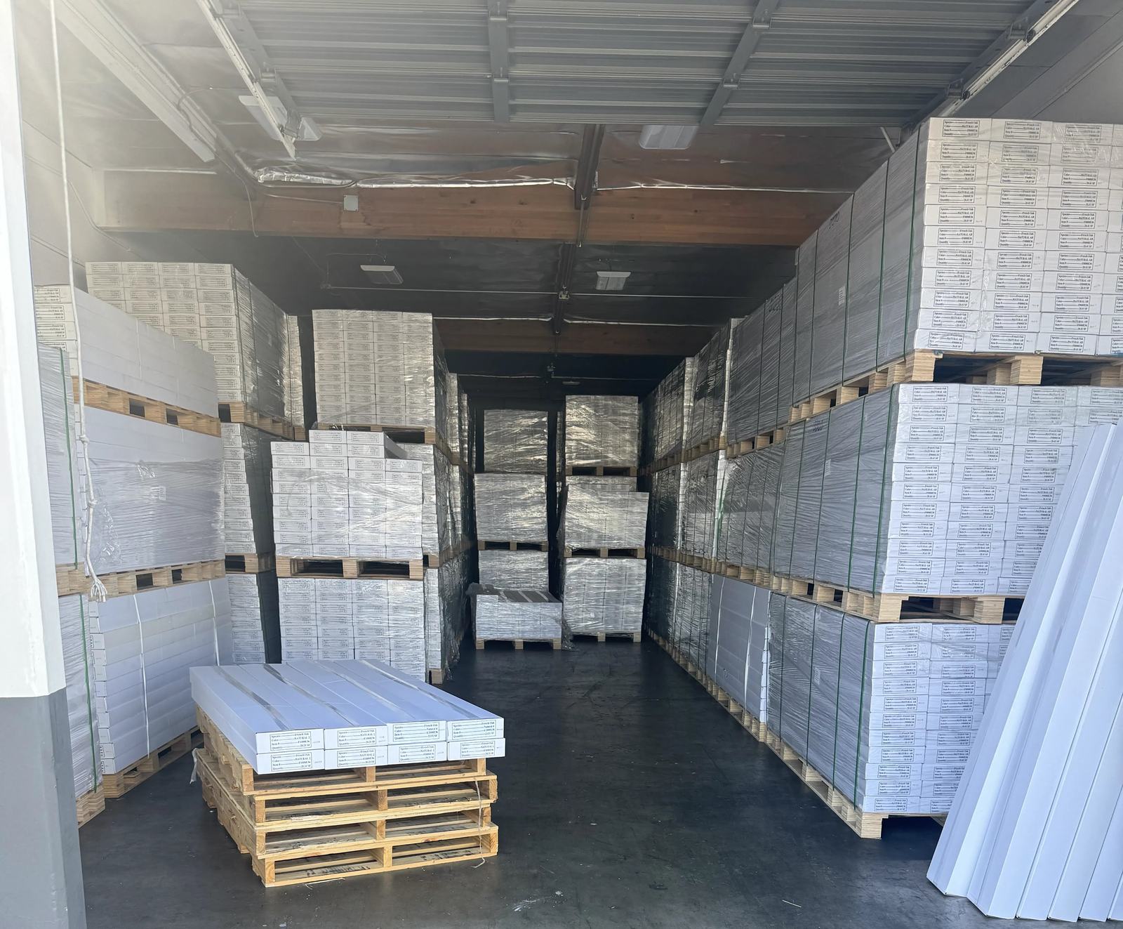 Pallets of boxed engineered wood flooring stacked to the ceiling in the Express Carpet warehouse