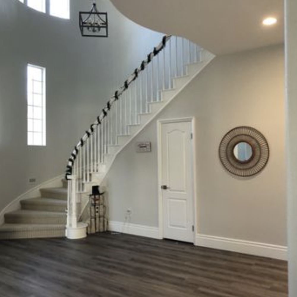 Curved staircase and entry with dark wide-plank flooring installed by Express Carpet